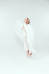 beautiful woman in angel costume with wings jumping isolated on white