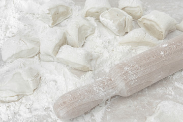 Cut unleavened dough on table. Rolling pin for dough.