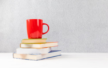 books with red cup on a table with gray background