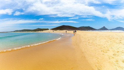 People walking on the beach towards Fingal Island at Fingal Bay, NSW, Australia