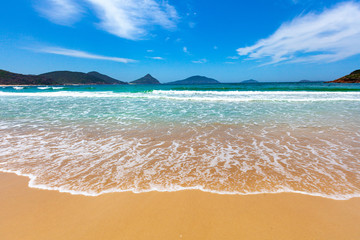 Waves wash onto the beautiful beach on bright summer day