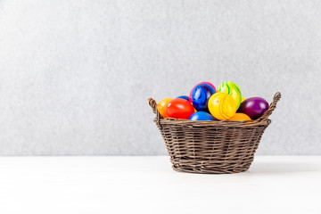 colorful easter eggs in a basket with gray background