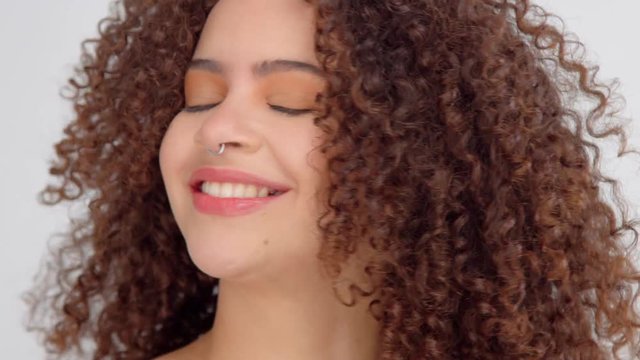 mixed race black woman with freckles and curly hair in studio making faces showing out her tongue and smiling