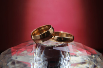 Wedding rings lie on a glass stand. Two gold rings on purple background