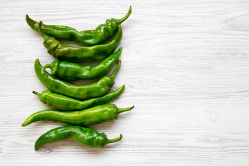 Green chili peppers on white wooden table, top view. Flat lay, from above, overhead. Copy space.