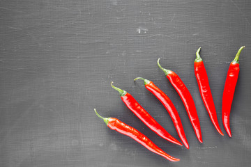 Hot red chili peppers on black background, top view. From above, overhead, flat lay. Copy space.