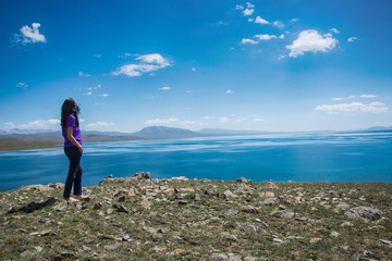 The girl walks on the Sonkul lake in the mountains.
