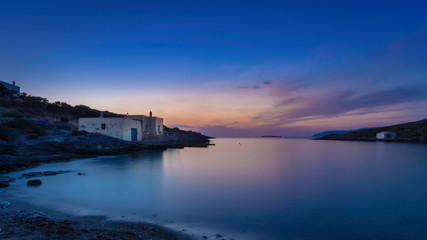 Fototapeta premium Just after sunset with some boathouses in the bay of Limnionas on the island Kythira, Greece, with a colorful blue and orange sky.