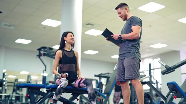 Personal trainer working with his client in gym. Personal fitness instructor.
