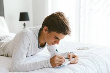 16 years old teenage boy writing school notes or doing homework
