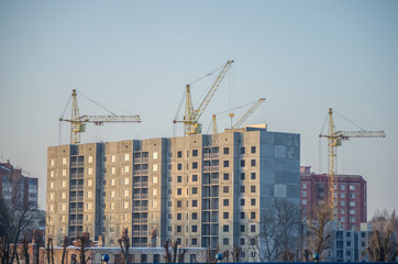 Fototapeta na wymiar Under construction high-rise building with yellow construction crane