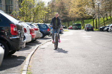 Naklejka premium Young woman on a Bicycle, riding around the city near the car