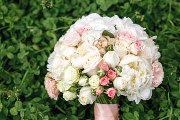 Wedding bouquet of white roses on the green clover field