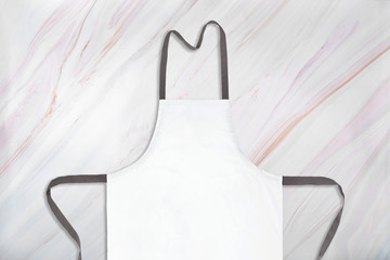 White apron on natural marble pattern background. Close-up of white aparon on marble texture. Flat...