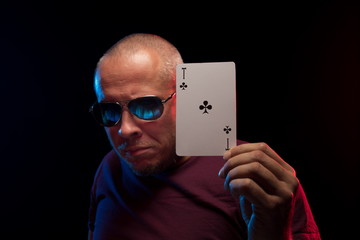 A man holds a deck of cards and shows tricks in a scenic light.