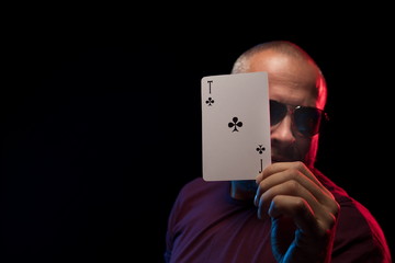 A man holds a deck of cards and shows tricks in a scenic light.