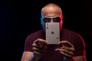 A man holds a deck of cards and shows tricks in a scenic light.