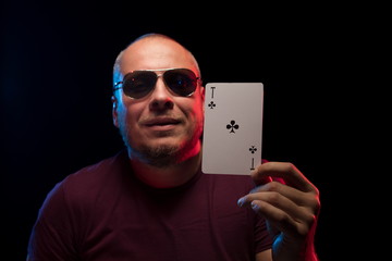 A man holds a deck of cards and shows tricks in a scenic light.