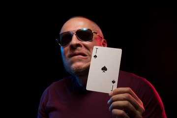 A man holds a deck of cards and shows tricks in a scenic light.