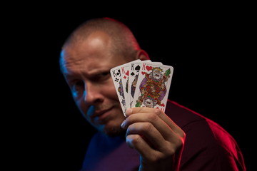 A man holds a deck of cards and shows tricks in a scenic light.
