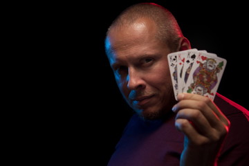 A man holds a deck of cards and shows tricks in a scenic light.