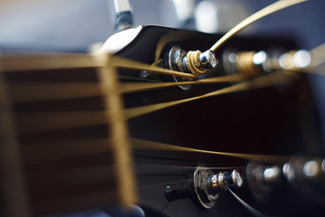 Black guitar neck, with stretched metal strings, on a blue background