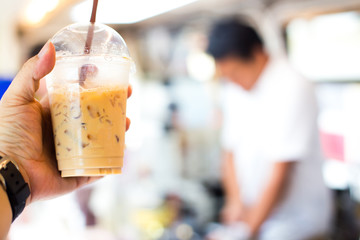 Cold coffee in plastic cup on a wooden table in cafe