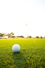 Gordijnen Green grass with golf ball close-up in soft focus at sunlight. Sport playground for golf club concept © NVB Stocker
