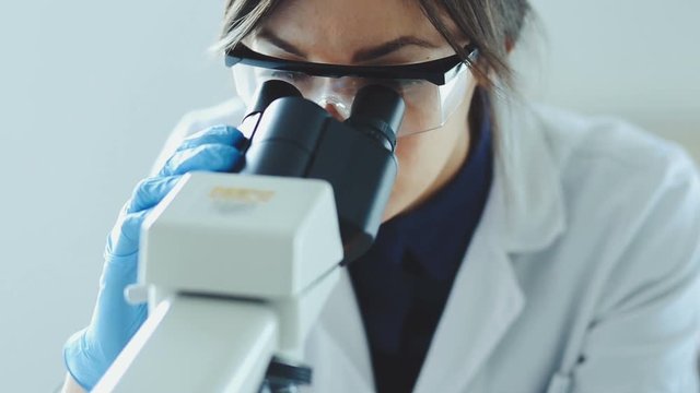 Young scientist looking through a microscope in a laboratory. Young scientist doing some research.