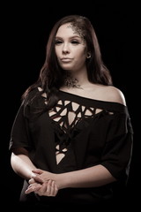 portrait of young brunette girl with black tears from eyes and lace pattern on face and neck posing...