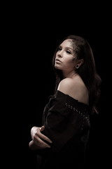 portrait of young brunette girl with black tears from eyes and lace pattern on face and neck posing...
