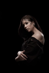 portrait of young brunette girl with black tears from eyes and lace pattern on face and neck posing...