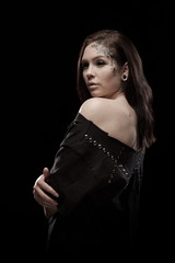 portrait of young brunette girl with black tears from eyes and lace pattern on face and neck posing...