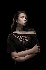 portrait of young brunette girl with black tears from eyes and lace pattern on face and neck posing...