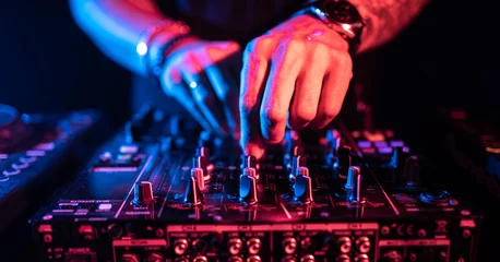  Close up of DJ hands controlling a music table in a night club. © MCStock