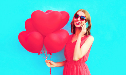 Portrait happy laughing woman calling on smartphone with pink heart shaped air balloons on colorful...