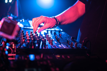 Fototapeta na wymiar Close up of DJ hands controlling a music table in a night club.