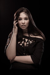 portrait of young brunette girl with black tears from eyes and lace pattern on face and neck posing...