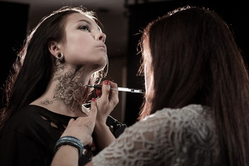 The artist on body painting draws on the face and neck drawing lace and flowers