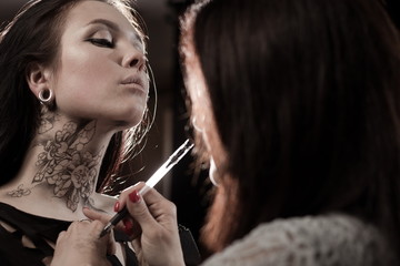 The artist on body painting draws on the face and neck drawing lace and flowers