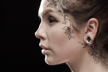 Beautiful portrait of a young brunette woman with black eyes and a lacy pattern on her face and...