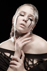 portrait of young brunette girl with black tears from eyes and lace pattern on face and neck posing...