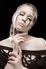 portrait of young brunette girl with black tears from eyes and lace pattern on face and neck posing...