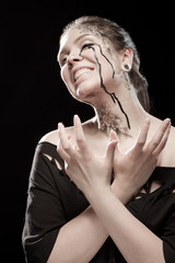 portrait of young brunette girl with black tears from eyes and lace pattern on face and neck posing...
