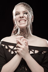 portrait of young brunette girl with black tears from eyes and lace pattern on face and neck posing...