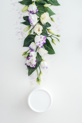 top view of composition with purple and white eustoma, beauty cream in bottle on white background