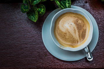 cup of coffee with cream on wooden background