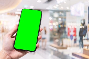 Close-up of female use smartphone blurred images in the mall and Clothes shop blur of the background.