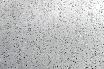 texture of rain drops on window glass over blur and cloudy sky background