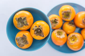 selective focus of whole and sweet persimmons on blue glass plates